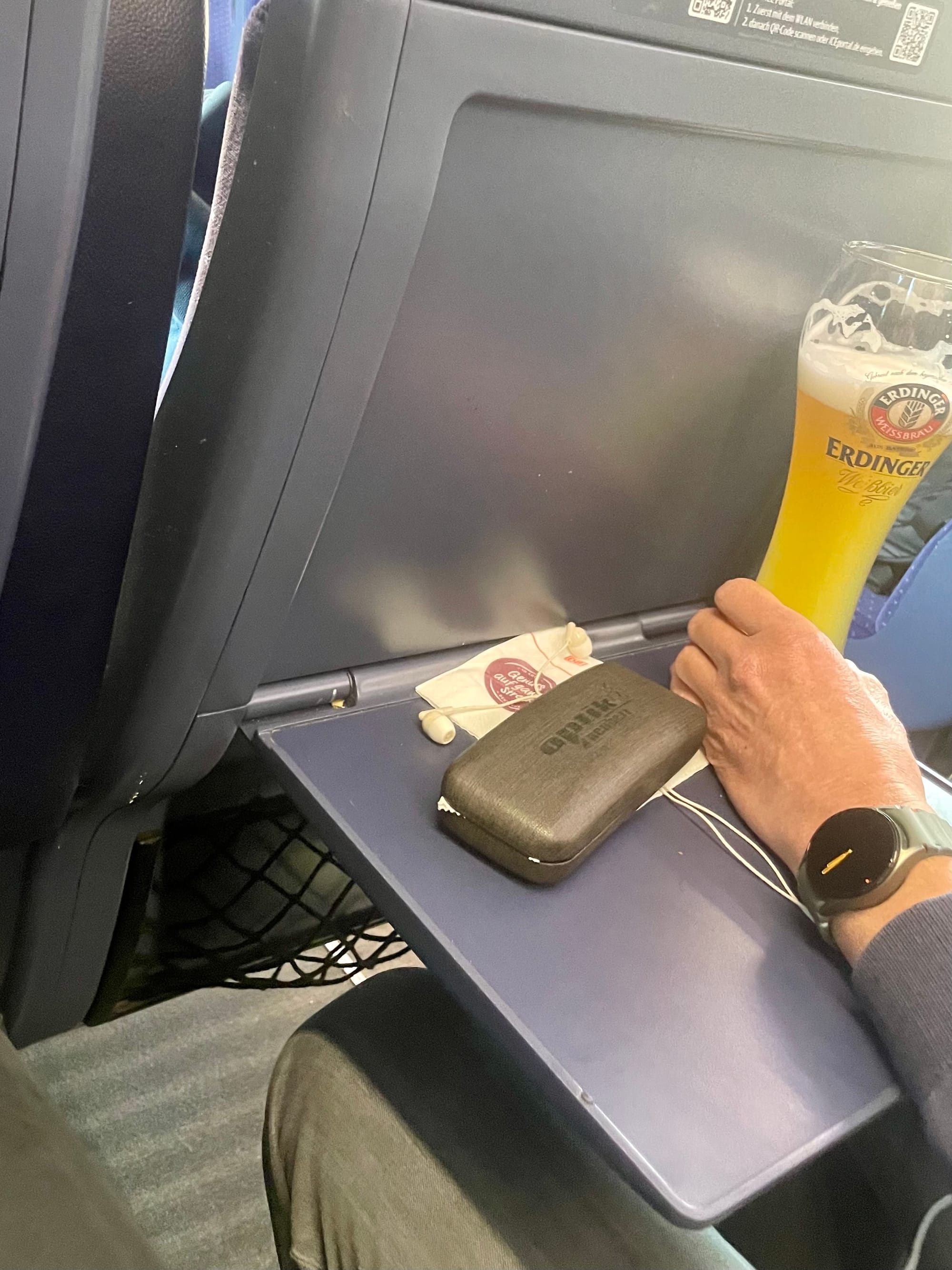 Jemand trinkt ein Erdinger Weißbier im Zug